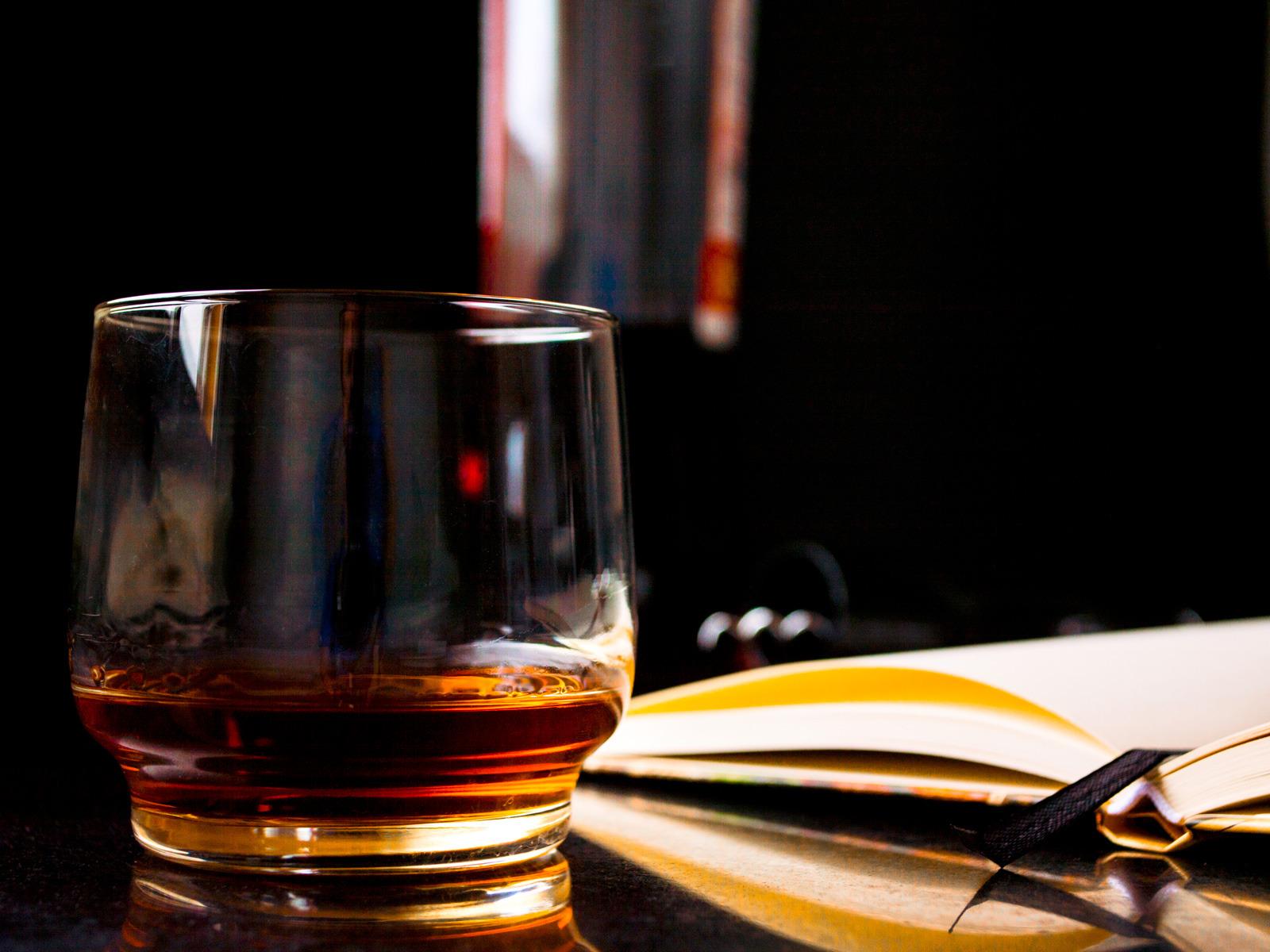 Szklanka whisky stoi obok otwartej książki © cromaconceptovisual/Pixabay