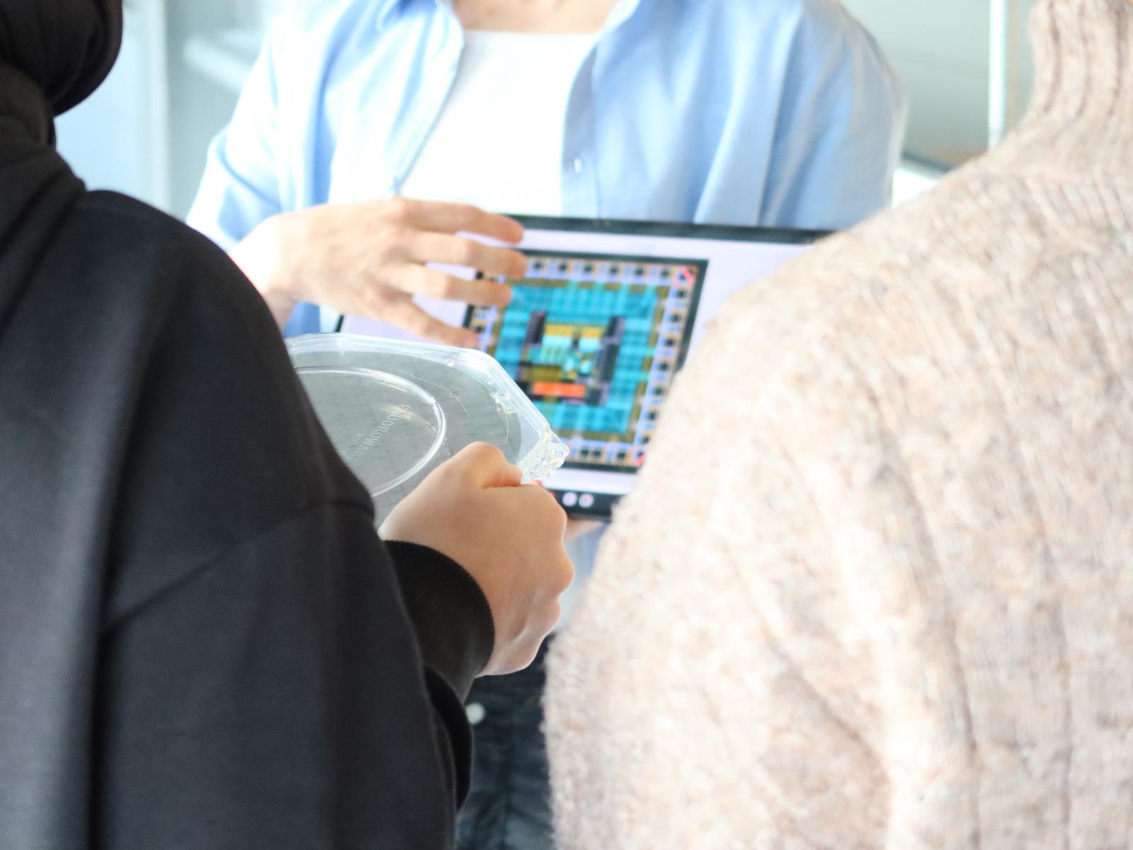 Forschung zum Anfassen: Während der Reinraumführung betrachten Schülerinnen einen Wafer aus der Nähe © IHP 2026/Juliane Schlegel