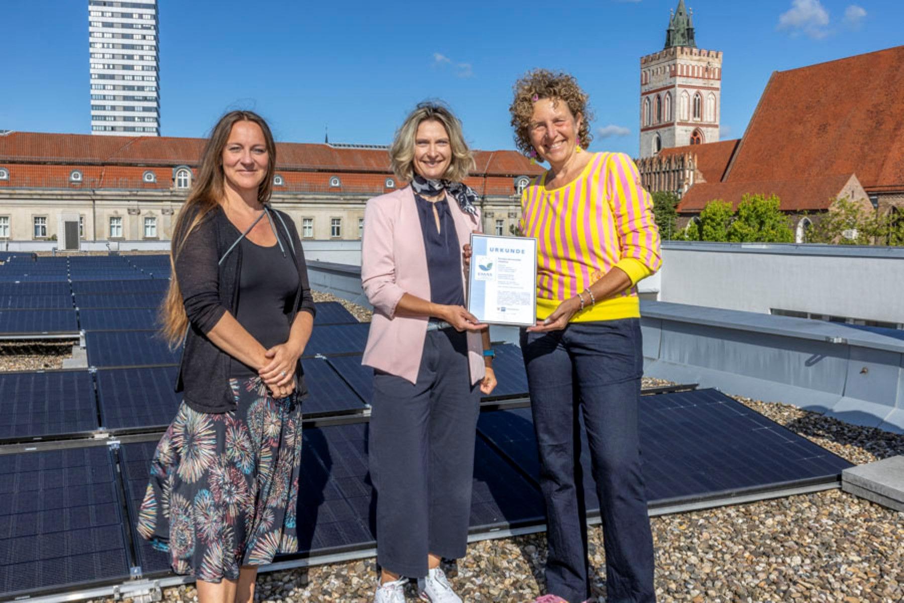 Viadrina-Vizepräsidentin Janine Nuyken (r.) mit der Geschäftsführerin der Industrie- und Handelskammer Ostbrandenburg, Monic Zweig (M.), und der Beauftragten für Nachhaltigkeit an der Viadrina, Sahra Damus, vor der Photovoltaikanlage auf dem Dach des Auditorium Maximum in Frankfurt (Oder)