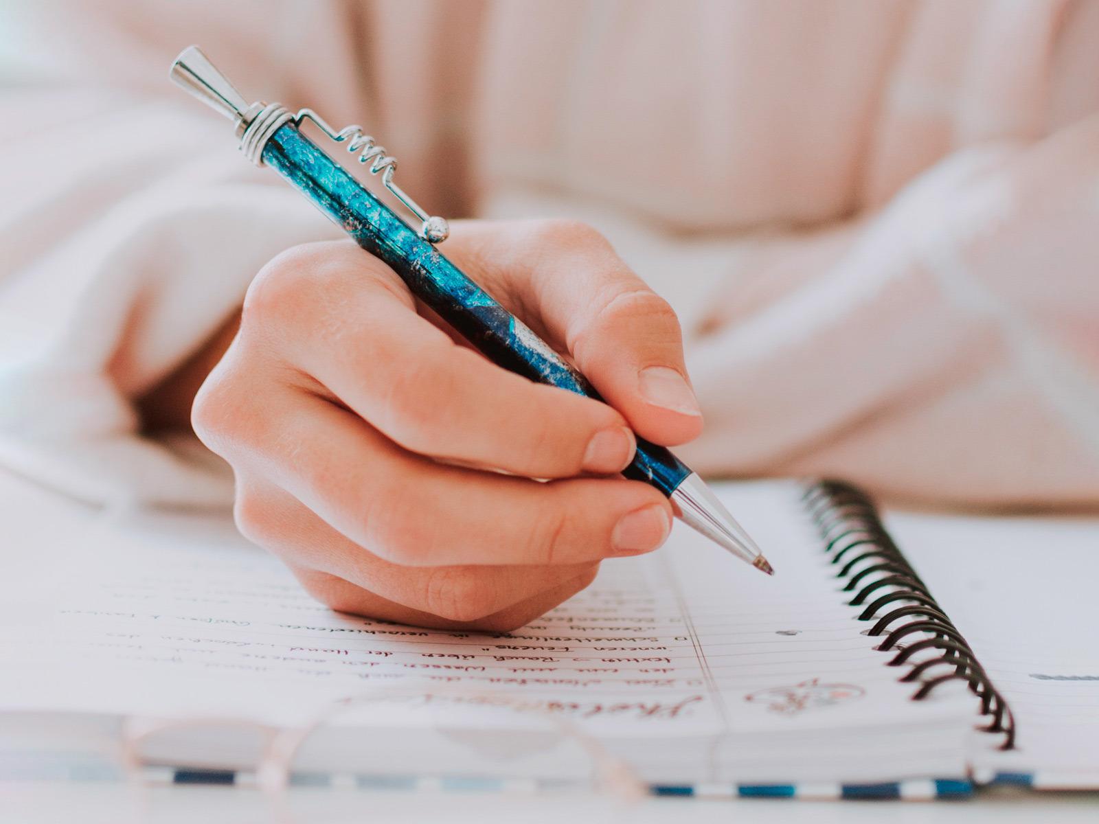Hand holding a pen over a notebook © fotografierende/Pixabay