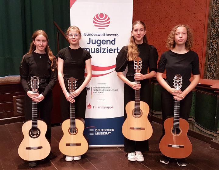 Zu sehen sind die Gitarristinnen Elisabeth Baltes, Marie Miethe, Elise Adele Sostaric und Nina Jenning