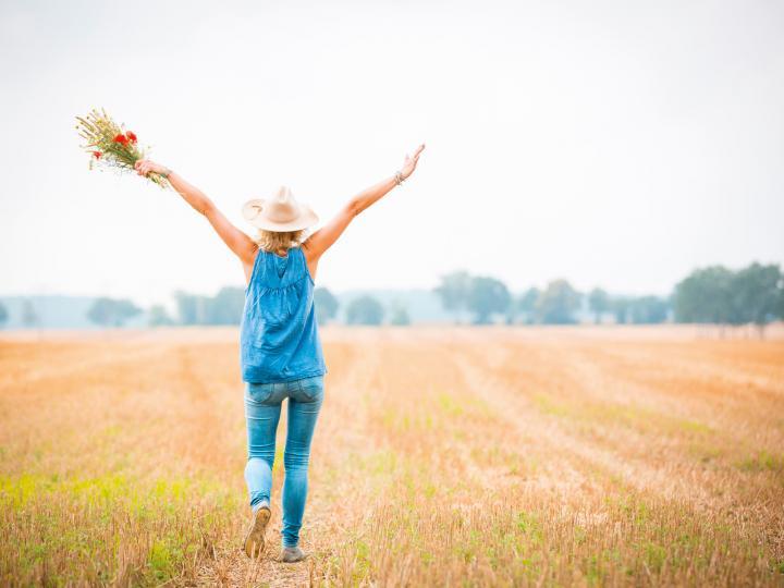 Szczęśliwa kobieta z kapeluszem i kwiatami na polu © Seenland Oder-Spree/Florian Läufer