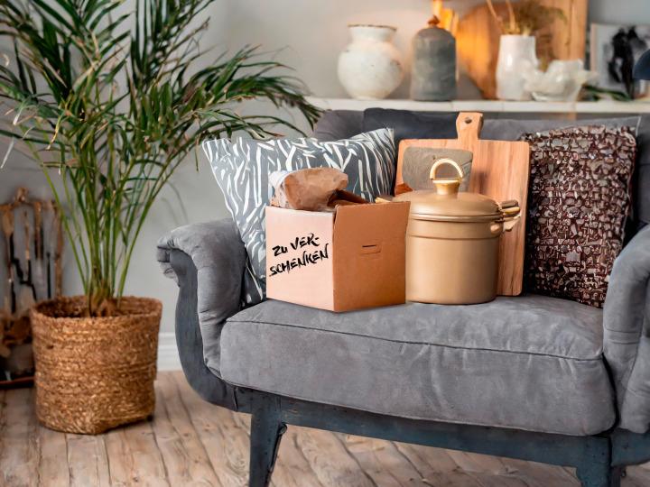 A couch and household items with a box that says "To give away" © Adobe Firefly