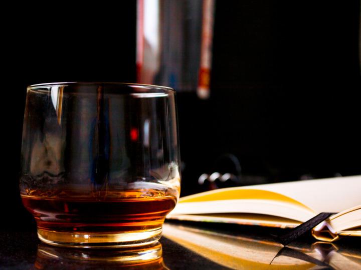 Ein Glas Whiskey steht neben einem aufgeschlagenen Buch © cromaconceptovisual/Pixabay