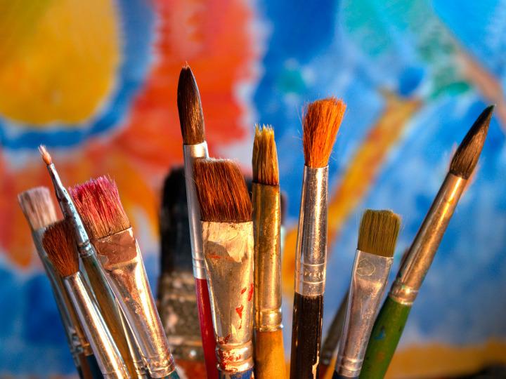 Several brushes in front of a painted picture © Pixabay