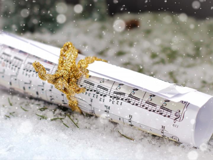 A rolled-up sheet of music with a gold ribbon in the snow © Van3ssa/Pixabay