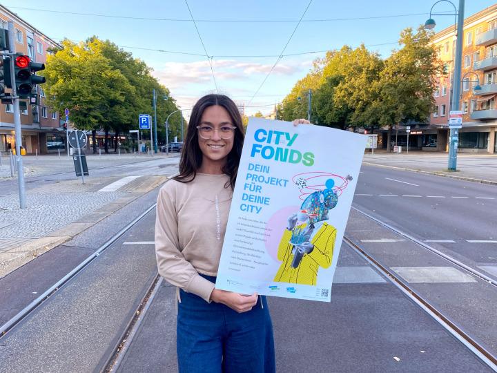 Kobieta trzyma plakat na temat funduszy miejskich © MuV